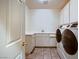 A bright laundry room includes counter space, cabinets, a sink, tile floor, and side-by-side washer and dryer at 386 Wiseton Ave, Las Vegas, NV 89183