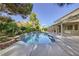 Lush backyard oasis with a sparkling pool, stone waterfall feature, covered patio, and beautiful landscaping at 386 Wiseton Ave, Las Vegas, NV 89183