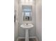 Clean, modern half-bathroom features a pedestal sink, large mirror, and neutral decor at 4634 Observed St, North Las Vegas, NV 89031