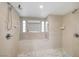 Bright bathroom featuring tile walls and floor with a tiled shower and window at 6771 Shelter Ln, Las Vegas, NV 89103