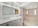 Bright bathroom featuring double sink vanity with white cabinetry and stone tiled shower with a window at 6771 Shelter Ln, Las Vegas, NV 89103