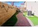 Inviting backyard featuring a brick-paved path, lush artificial grass, ambient string lights and an A/C unit at 7257 Early Pioneer Ave, Las Vegas, NV 89129