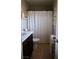 Compact bathroom featuring dark vanity and a white shower curtain, complemented by rustic accents and tile floors at 7257 Early Pioneer Ave, Las Vegas, NV 89129