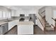 Modern kitchen with white cabinets, stainless steel appliances, a center island and staircase access at 7257 Early Pioneer Ave, Las Vegas, NV 89129