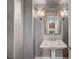 Elegant powder room featuring pedestal sink, decorative mirror, and stylish sconces at 9201 Tesoras Dr # 401, Las Vegas, NV 89144