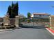 View of the community entrance gate featuring stone columns, desert landscaping, and red paved streets at 9236 Canalino Dr, Las Vegas, NV 89134