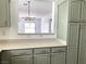 Modern kitchen with a view into the living room and sage green cabinets with gold hardware at 9236 Canalino Dr, Las Vegas, NV 89134