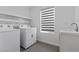 Well-lit laundry room with modern washer, dryer, sink and shelving at 9430 Isla Lee Ave, Las Vegas, NV 89178