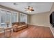 Cozy living room featuring hardwood floors, a ceiling fan, and large windows with plantation shutters at 9893 Santa Ponsa Ct, Las Vegas, NV 89178