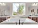 Bright and airy bathroom featuring a soaking tub, dual vanities, and large window with view at , Las Vegas, NV 89113