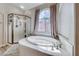 Bathroom features a corner shower, a large soaking tub under a window, and modern fixtures at 1033 Logan Patrick Dr, Henderson, NV 89052