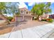 Inviting home featuring a two-car garage, brick driveway, and mature landscaping under a blue sky at 1033 Logan Patrick Dr, Henderson, NV 89052