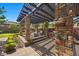 Inviting covered outdoor patio with stone pillars, a fire pit, built in grill, and comfortable seating at 10470 Dove Meadow Way, Las Vegas, NV 89135