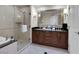 Well-lit bathroom showcasing a double vanity, large mirror, and glass-enclosed shower and tub at 145 E Harmon Ave # 409, Las Vegas, NV 89109