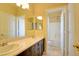 Bathroom featuring double sinks, wood cabinets, a large mirror, and an adjoining bathroom with a shower and tub at 153 Cascade Lake St, Las Vegas, NV 89148