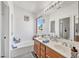 Bright bathroom with double sinks, large mirror, and tiled tub at 2180 Polynesia Cir, Henderson, NV 89074