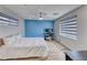 A well-lit bedroom featuring wood floors, a ceiling fan, and a serene blue accent wall at 2637 Via Monet, Henderson, NV 89044