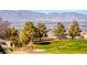 Expansive backyard view showcasing lush green grass, mature trees, and panoramic mountain vistas in a serene setting at 2702 Grand Forks Rd, Henderson, NV 89052