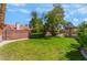 Private backyard featuring a well-manicured lawn, mature trees, and brick perimeter wall at 3108 Leafwood St, Las Vegas, NV 89108