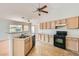 Open kitchen with light wood cabinets, breakfast bar, and black appliances at 3912 Branchwood Dr, North Las Vegas, NV 89032