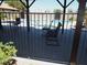 Community pool area view from under the covered patio, shows lounge chairs and a table behind a security fence at 3954 Saddlewood Ct, Las Vegas, NV 89121