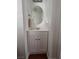 Bathroom with a compact white vanity, oval mirror, and wood-look flooring at 4284 Parkdale Ave, Las Vegas, NV 89121