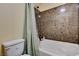 Bathroom with a bathtub and shower, featuring stone-style tile and a neutral-colored shower curtain at 5448 Tulip Hill Ave, Las Vegas, NV 89141