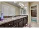 Bathroom with a double sink vanity, granite countertop, large mirror, and view into the tiled shower at 5448 Tulip Hill Ave, Las Vegas, NV 89141