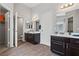 A modern bathroom with dual sinks, dark cabinetry, and wood-look floors offers both style and functionality at 556 Decidedly St, Henderson, NV 89015