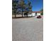 Wide exterior shot featuring a charming white house, gravel yard, and a neatly parked red lawn mower at 626 Kimberly Ave, Pahrump, NV 89060