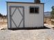 External view of a white storage building with grey trim and a diamond pattern on the door at 626 Kimberly Ave, Pahrump, NV 89060