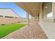 Long patio with brick flooring and a covered area, overlooking the artificial turf in the backyard at 717 Monroe Hill Pl, Henderson, NV 89011