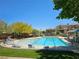 Relaxing community pool area with plenty of lounge chairs, green lawns, and mature trees for shade at 7461 Enviable Ct, Las Vegas, NV 89149