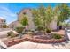A side view of a two-story home with a well-landscaped yard, featuring trees, shrubs, and decorative brick edging at 7909 Citrus Meadow Ct, Las Vegas, NV 89131