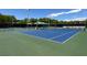 Well-maintained tennis court with blue surface, surrounded by green fencing and lush trees, perfect for outdoor recreation at 7909 Citrus Meadow Ct, Las Vegas, NV 89131