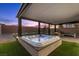 Luxurious hot tub with stone surround under a covered patio, complemented by a fire pit and plush seating at 8013 Green River Knob St, Las Vegas, NV 89113