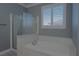 This is a bathroom featuring a shower and a tub with a window with white shutters at 8228 Fulton Ranch St, Las Vegas, NV 89131