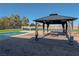 Gazebo with lights and drapes next to a pool, artificial grass and a tennis court at 8228 Fulton Ranch St, Las Vegas, NV 89131
