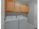 Laundry room has wooden cabinets, white washer and dryer, and tiled flooring at 8228 Fulton Ranch St, Las Vegas, NV 89131