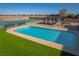 A refreshing pool sits next to a tennis court and charming gazebo, complemented by lush artificial grass at 8228 Fulton Ranch St, Las Vegas, NV 89131