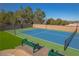 Well-maintained tennis court with green benches and a brick retaining wall at 8228 Fulton Ranch St, Las Vegas, NV 89131