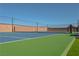 Green and blue tennis court surrounded by block wall, with artificial grass, and tennis net at 8228 Fulton Ranch St, Las Vegas, NV 89131