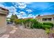 This backyard offers beautiful landscaping, with decorative rock, flowering bushes, and a covered patio for relaxing at 8525 Festival Dr, Las Vegas, NV 89134