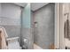 Modern bathroom with gray tiled walls, glass shower enclosure, and toilet at 8525 Festival Dr, Las Vegas, NV 89134