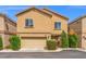 View of a tan two-story home showcasing a two-car garage and manicured bushes at 9457 Alma Ridge Ave, Las Vegas, NV 89178