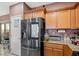 This modern kitchen boasts a smart stainless steel refrigerator, granite countertops, and wooden cabinets at 9457 Alma Ridge Ave, Las Vegas, NV 89178