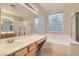 Bathroom with double sinks, bathtub, glass block window, and shower; bright and functional at 10212 Donald Weese Ct, Las Vegas, NV 89129
