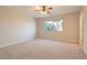 Spacious, carpeted bedroom featuring a ceiling fan and large window with a view of lush greenery at 10212 Donald Weese Ct, Las Vegas, NV 89129