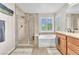 Bright bathroom featuring a soaking tub, walk-in shower, and double windows with natural light at 10353 Settlers Run Ave, Las Vegas, NV 89166