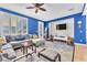 Cozy living room with a comfortable sectional sofa, bright blue accent wall, and lots of natural light at 10353 Settlers Run Ave, Las Vegas, NV 89166